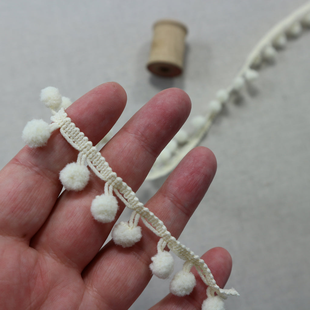 mini ivory Pom pom trim with hand for scale