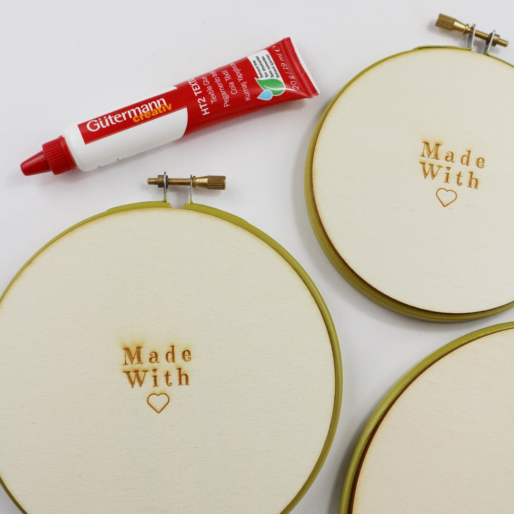 Green embroidery hoop with wooden back and textile glue.