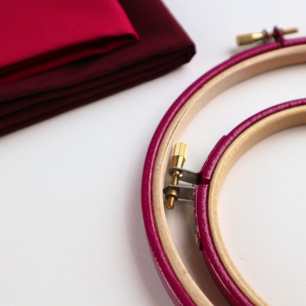 pink coloured embroidery thread with red Kona cotton fabric in the background.