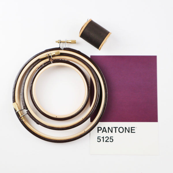 three very dark red embroidery hoops with a Pantone shade card.