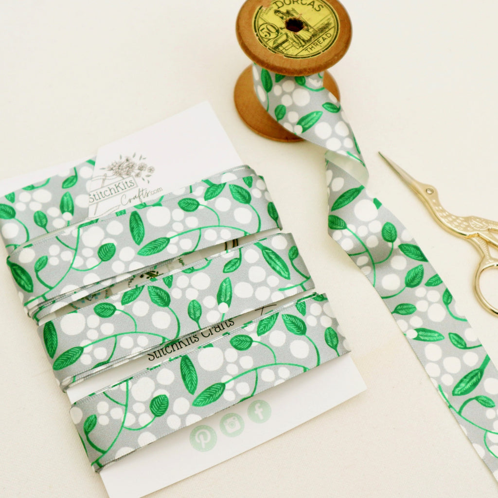5 meters of satin ribbon with a white berry and leaf design on a silver grey background