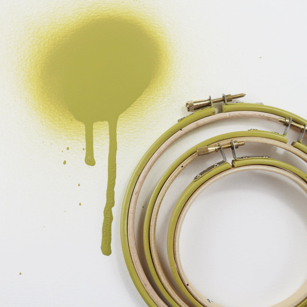 Three painted embroidery hoop with mustard spray paint.