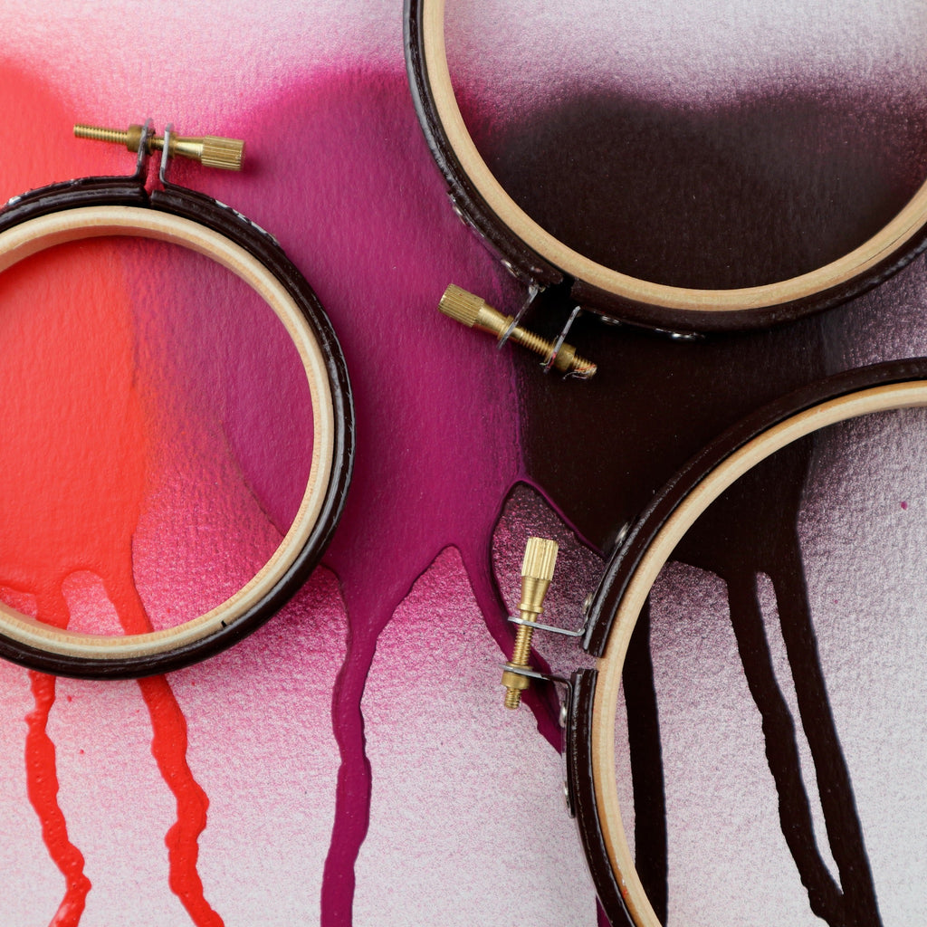 coloured embroidery hoops on a spray painted graffiti background.