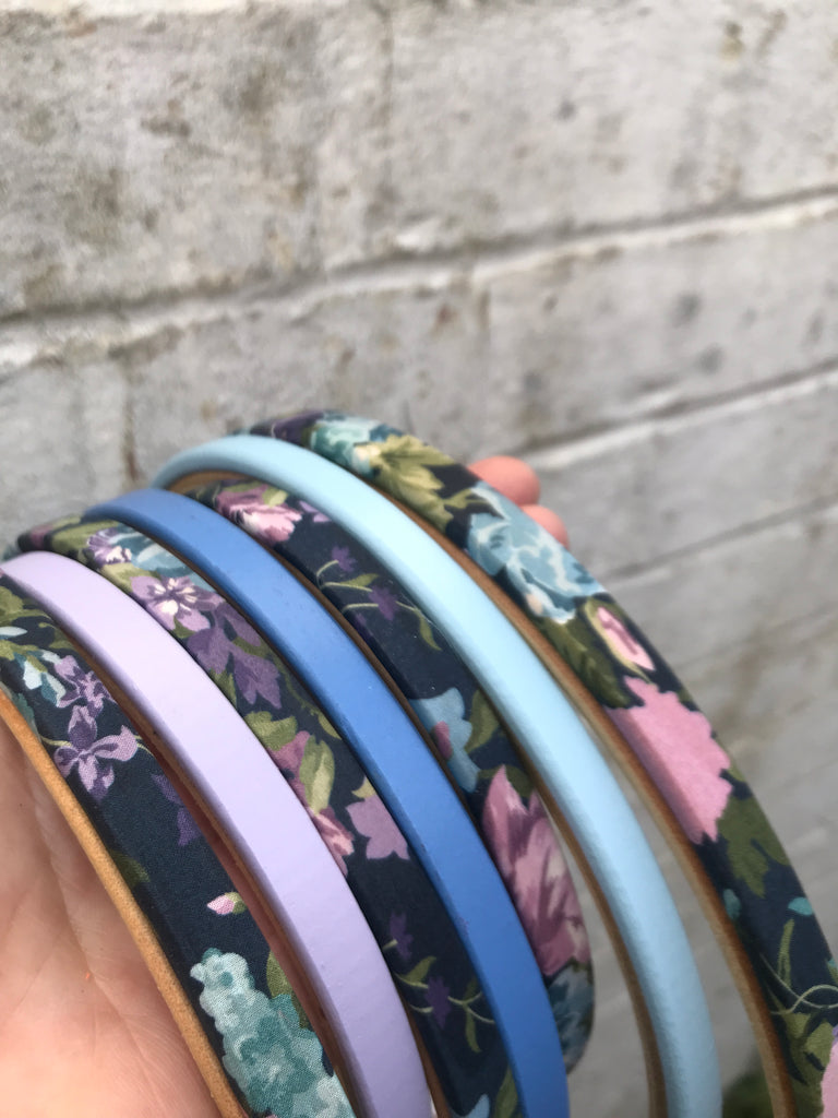 Set of floral-patterned headbands in various colors on a textured surface.