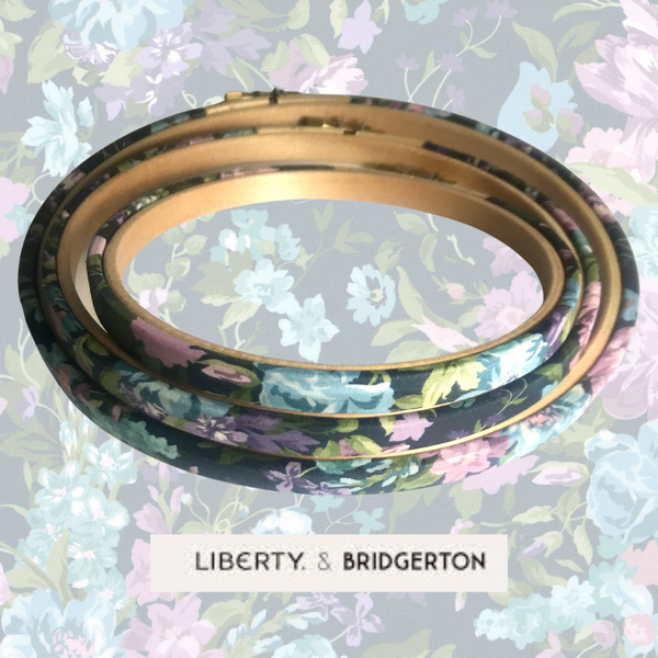 Decorative embroidery hoops with floral patterns on a floral background, featuring the 'Liberty & Bridgerton' fabric