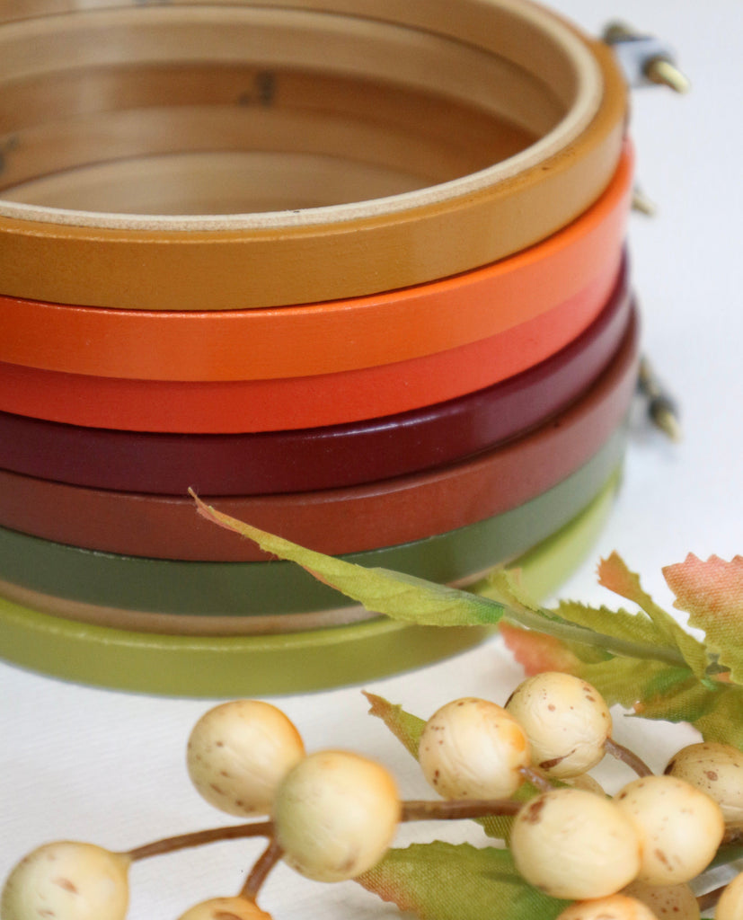 Stack of colorful painted embroidery hoop with a branch of berries on a light background