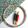 Embroidery hoop with  green and red holly leaf patterned fabric.