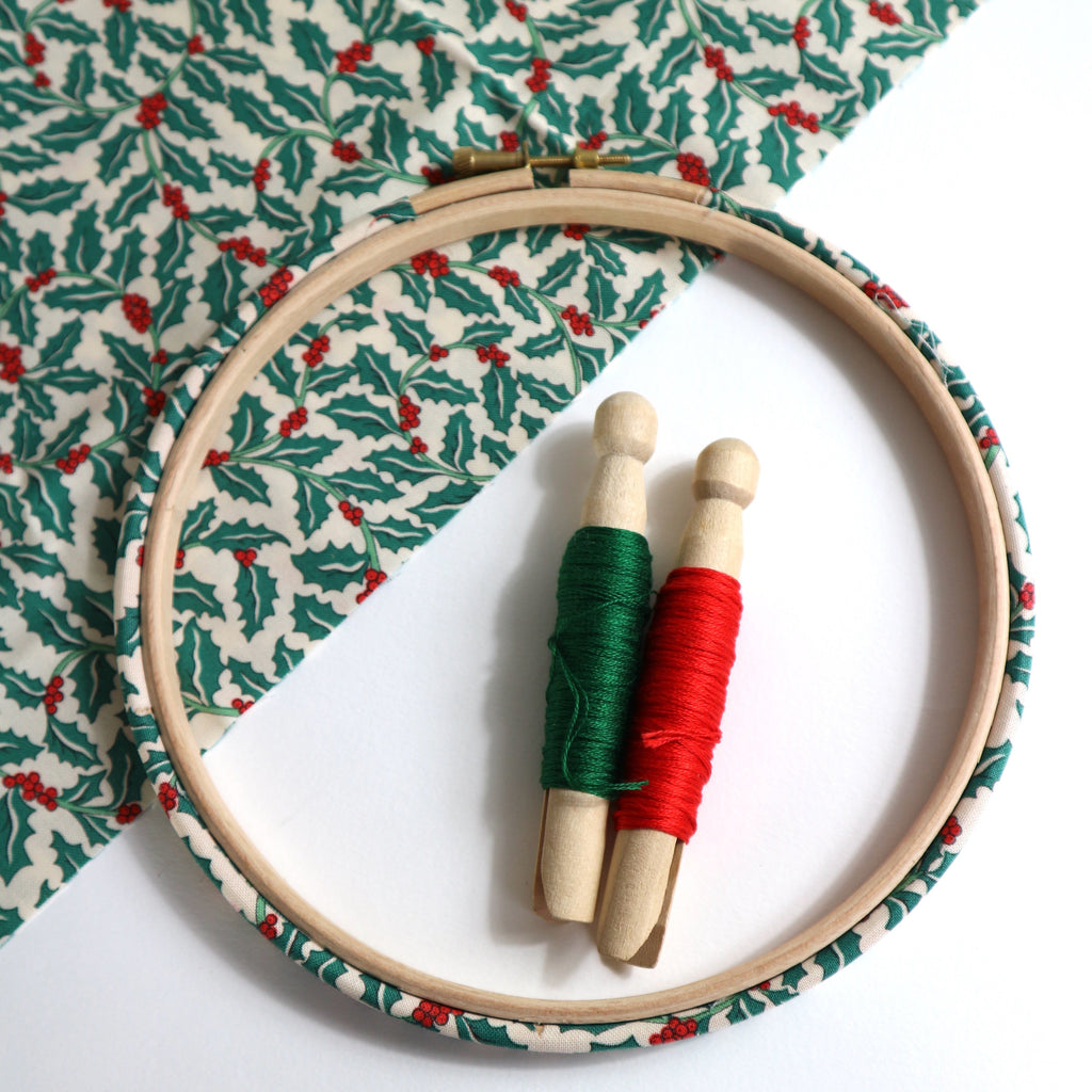 Embroidery hoop with  green and red holly leaf patterned fabric.
