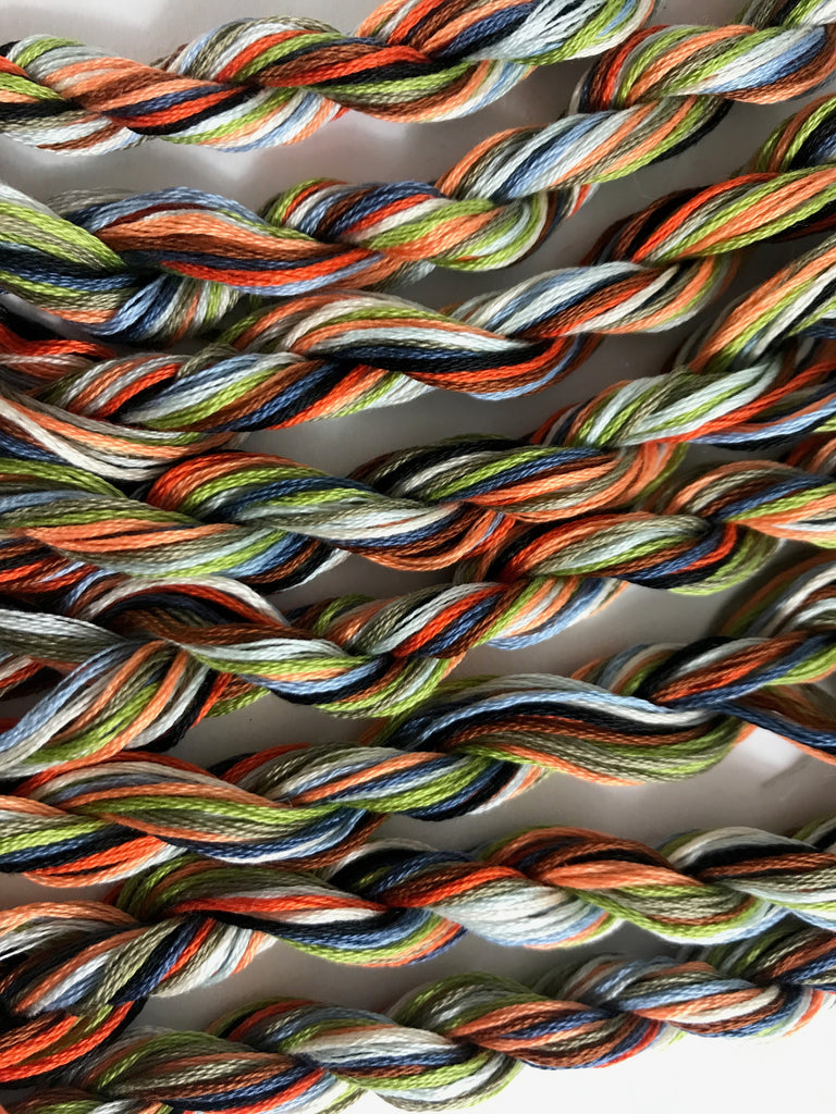 Close-up of multicolored braided embroidery floss on a white background