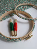 Embroidery hoops with red and green thread on a holly patterned fabric background