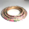Stack of floral-patterned embroidery hoops on a pale pink background
