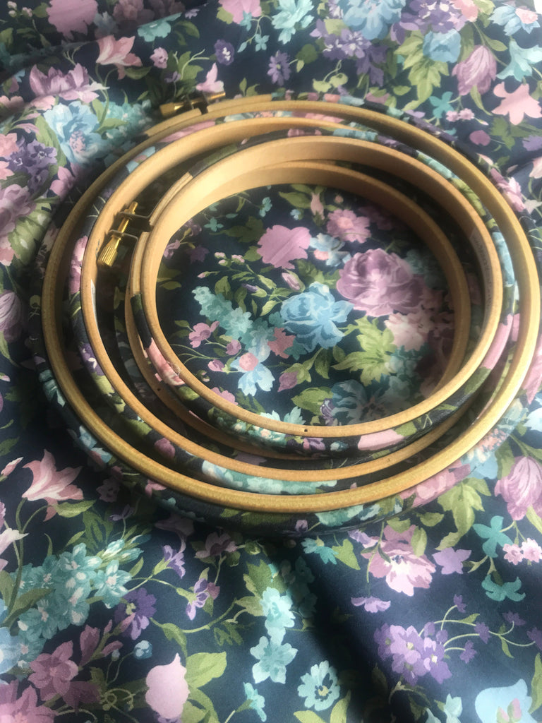 Set of wooden embroidery hoops on a floral fabric background
