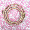 pink colored fabric-covered embroidery hoop with a floral Tana Lawn print background.