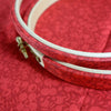 Embroidery hoop with white thread on a red fabric background