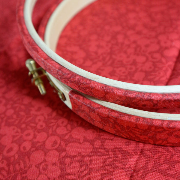 Embroidery hoop with white thread on a red fabric background