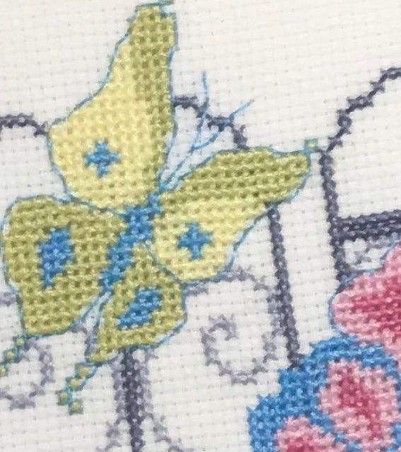 Close up of a yellow green and blue butterfly stitched in cross stitch