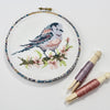 British garden bird cross stitch hoop with threads on a pedi bobbins.