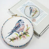 Bird Cross-Stitch in a hoop, propped on kit box.