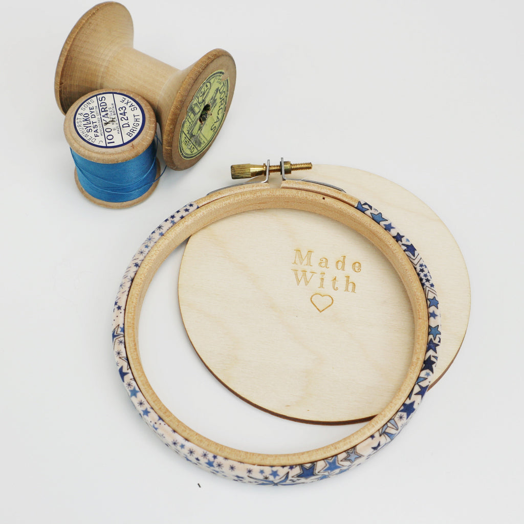 a decorative blue embroidey hoop with a wooden back and vintage bobbins