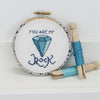 Embroidery hoop with cross-stitched message 'You are my rock' featuring a blue gemstone design on a white background.