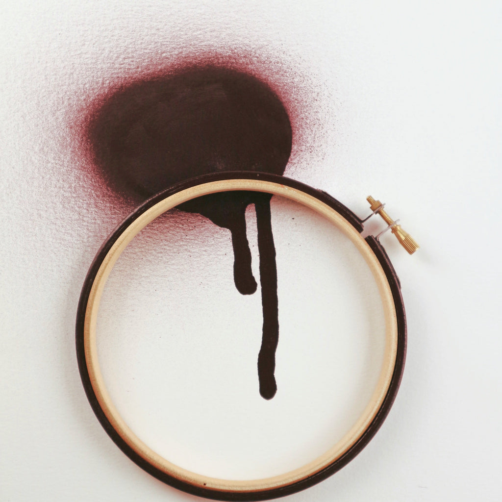 Dark red coloured embroidery hoop with spray painted background.