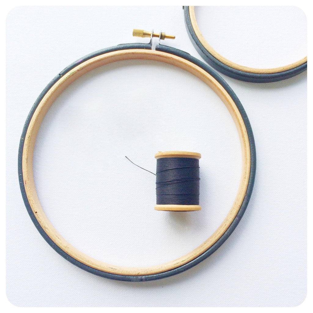 Dark grey painted embroidery hoops with a cotton reel