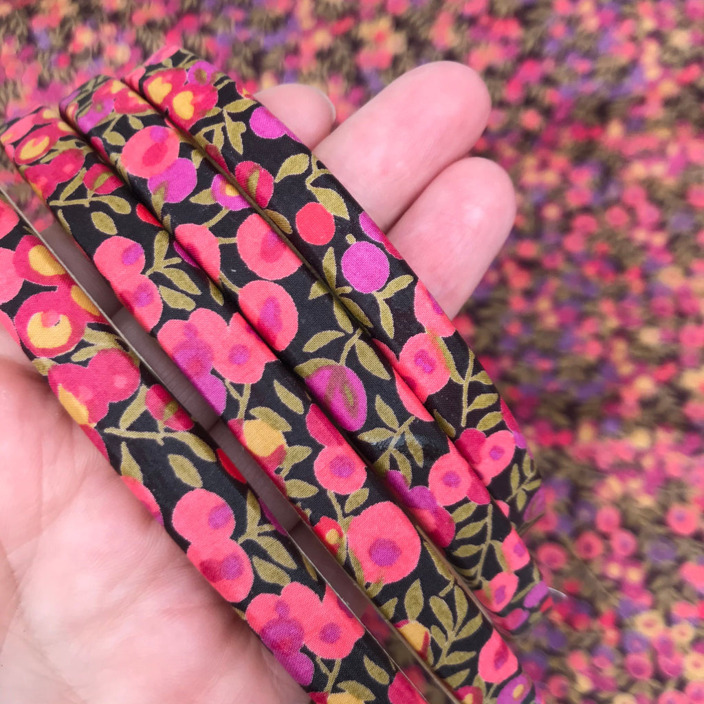 Floral-patterned embroidery hoops held in a hand with a blurred floral background.