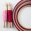 three pink wooden embroidery hoops with embroidery threads on pegs.